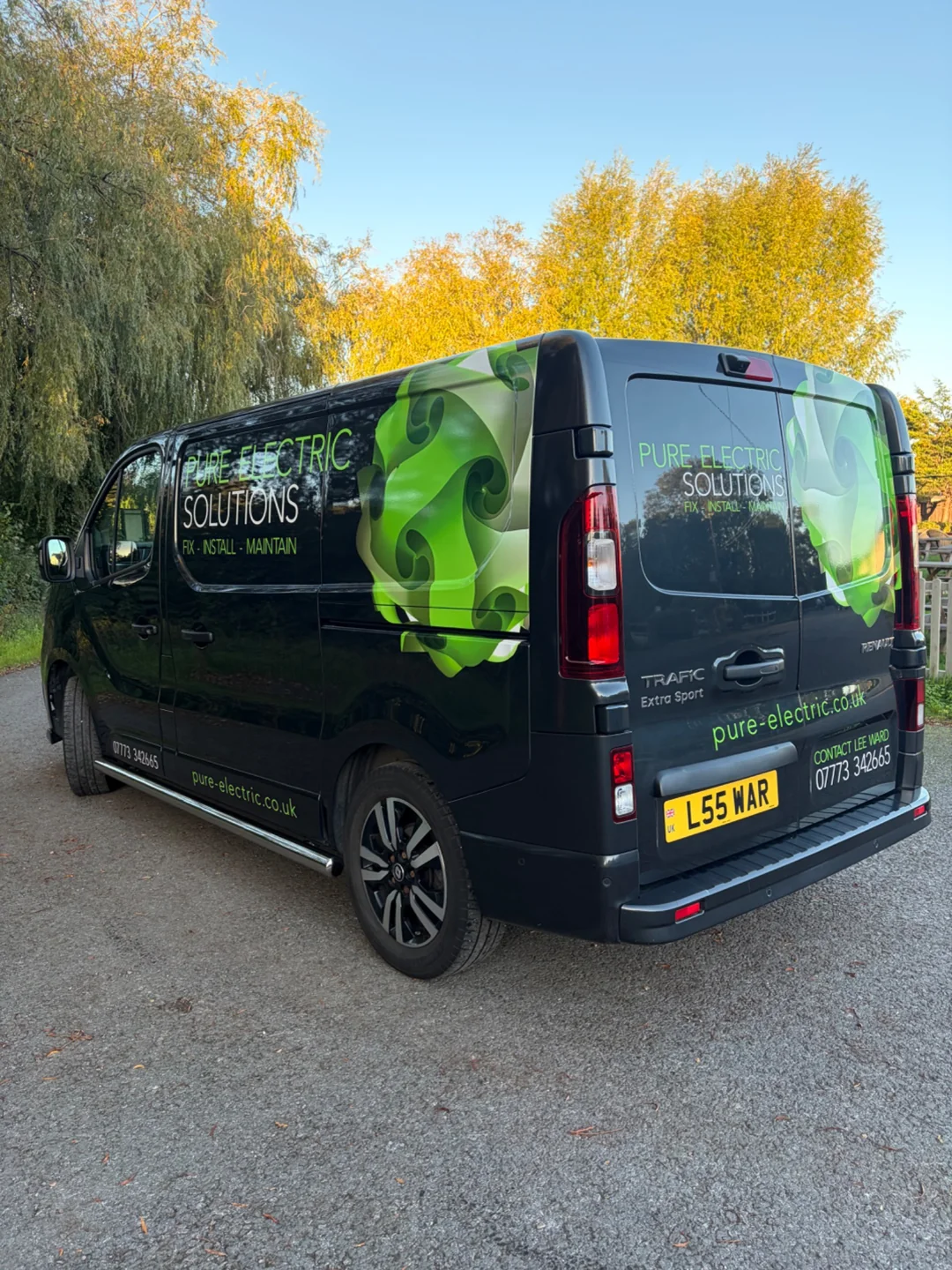 Rear and side of the Pure Electric Solutions van beside autumn trees